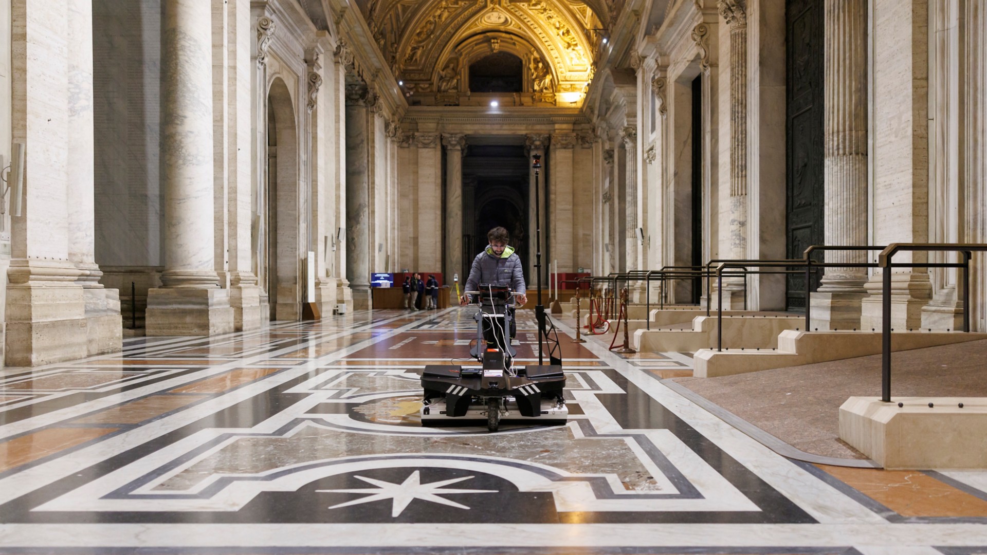 A technician operates a robotic vehicle across the marble flooring of St. Peter's Basilica