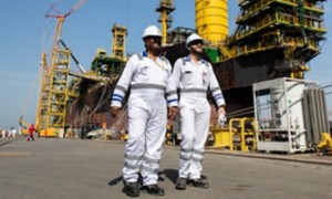 Workers walk in port in front of the ship