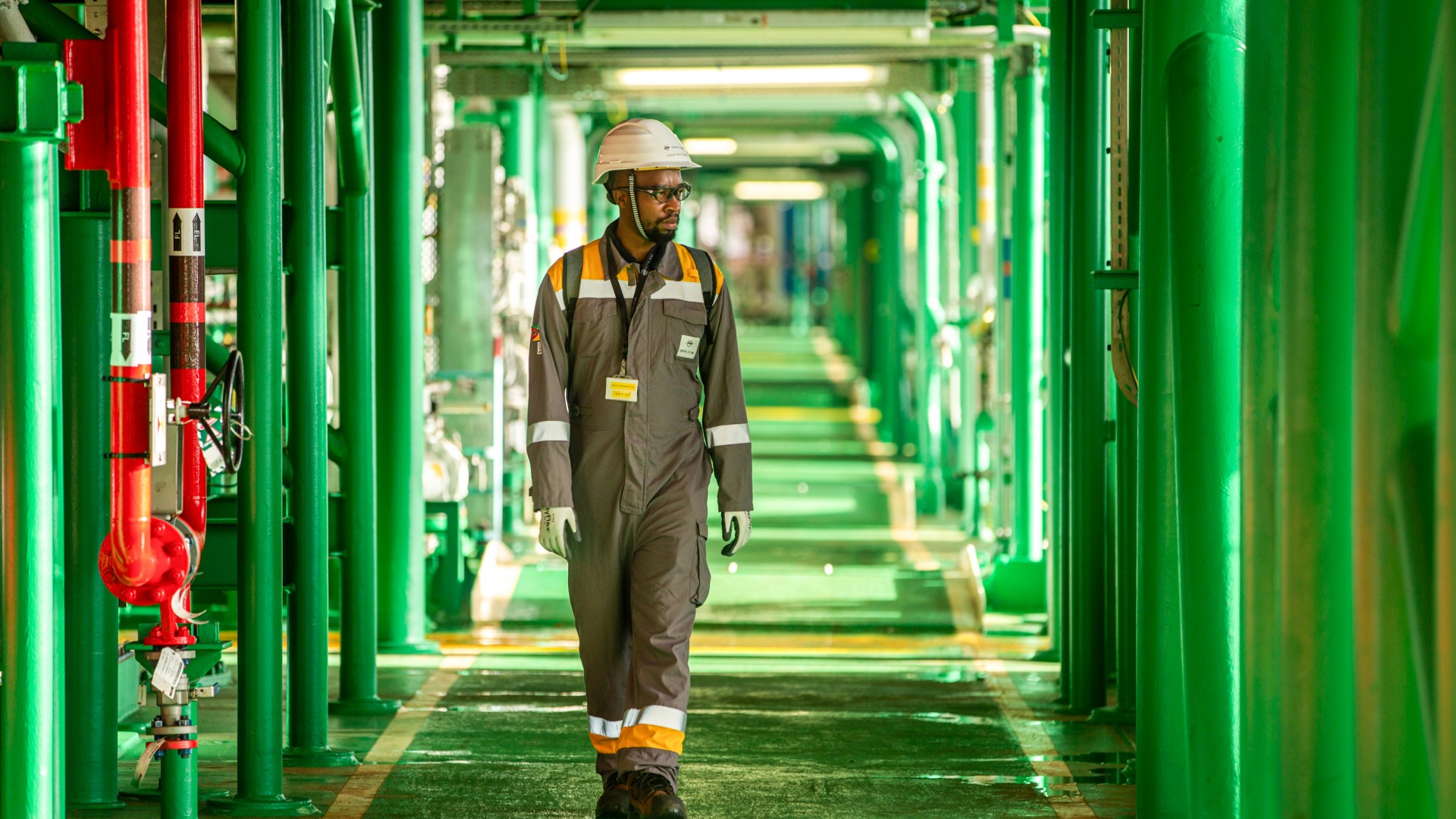 tecnico africano cammina in corridoio sotto raffineria