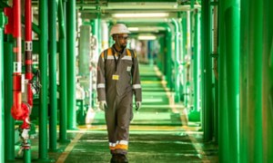 Mozambican technician walks along a green corridor inside a plant