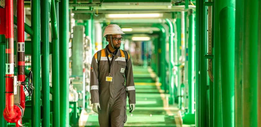 Mozambican technician walks along a green corridor inside a plant