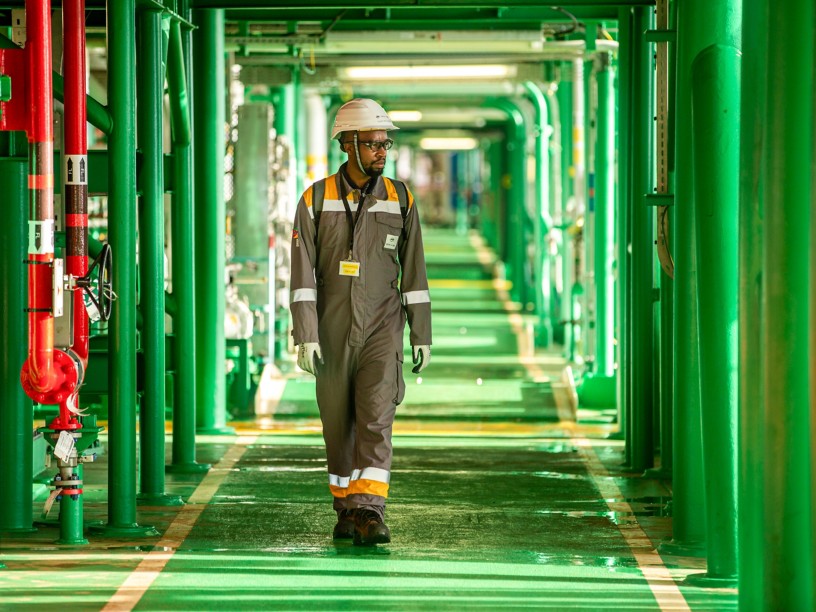 Tecnico mozambicano cammina lungo un corridoio verde all'interno di un impianto
