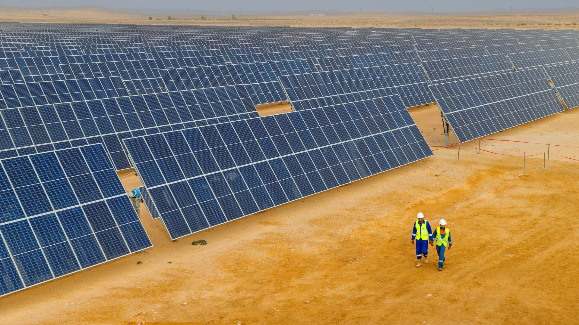 Operai che camminano nell’impianto di pannelli solari nel deserto tunisino