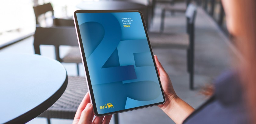 Persona seduta al tavolo tiene un tablet con la copertina di un report annuale 2025 su sfondo blu