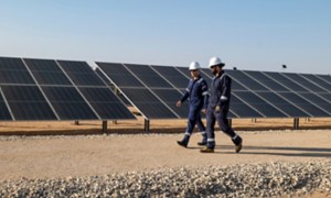 Due operai attraversano l'impianto fotovoltaico