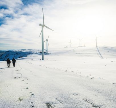 Due persone camminano nell’impianto eolico sulla neve