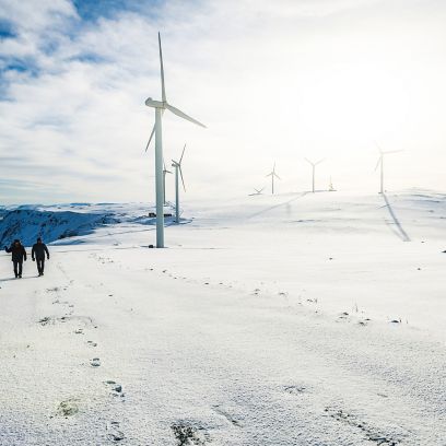 Due persone camminano nell’impianto eolico sulla neve