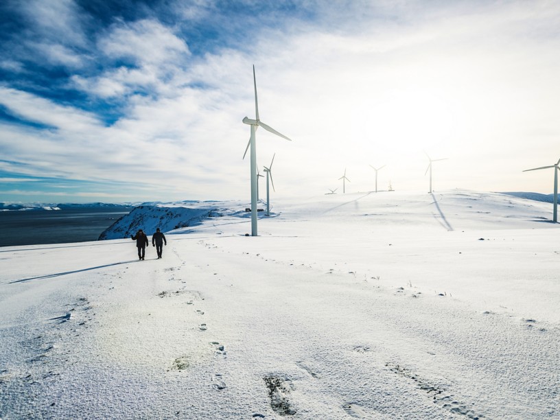 Due persone camminano nell’impianto eolico sulla neve