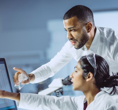 Two scientists man and woman inside the laboratory look at the computer screen