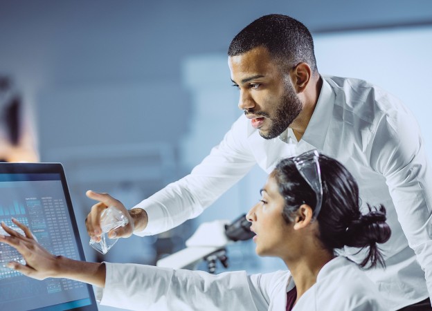 Two scientists man and woman inside the laboratory look at the computer screen