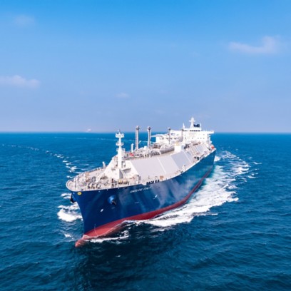A large liquefied natural gas (LNG) carrier sailing in open sea under a clear blue sky.
