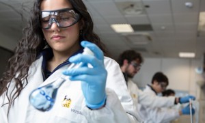 Scienziata guarda provetta in laboratorio