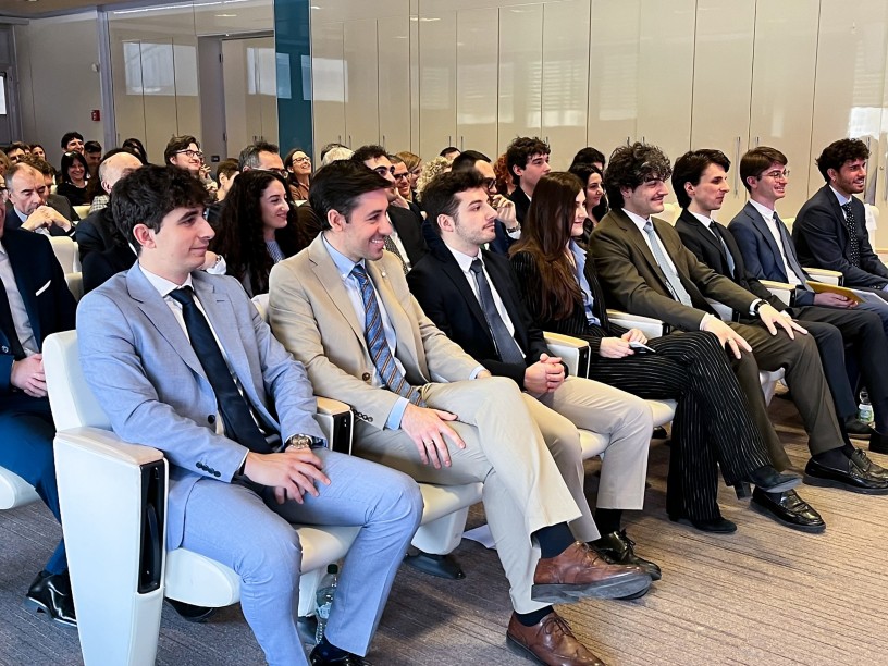 Persone sedute in una sala mentre assistono a un evento o a una presentazione.