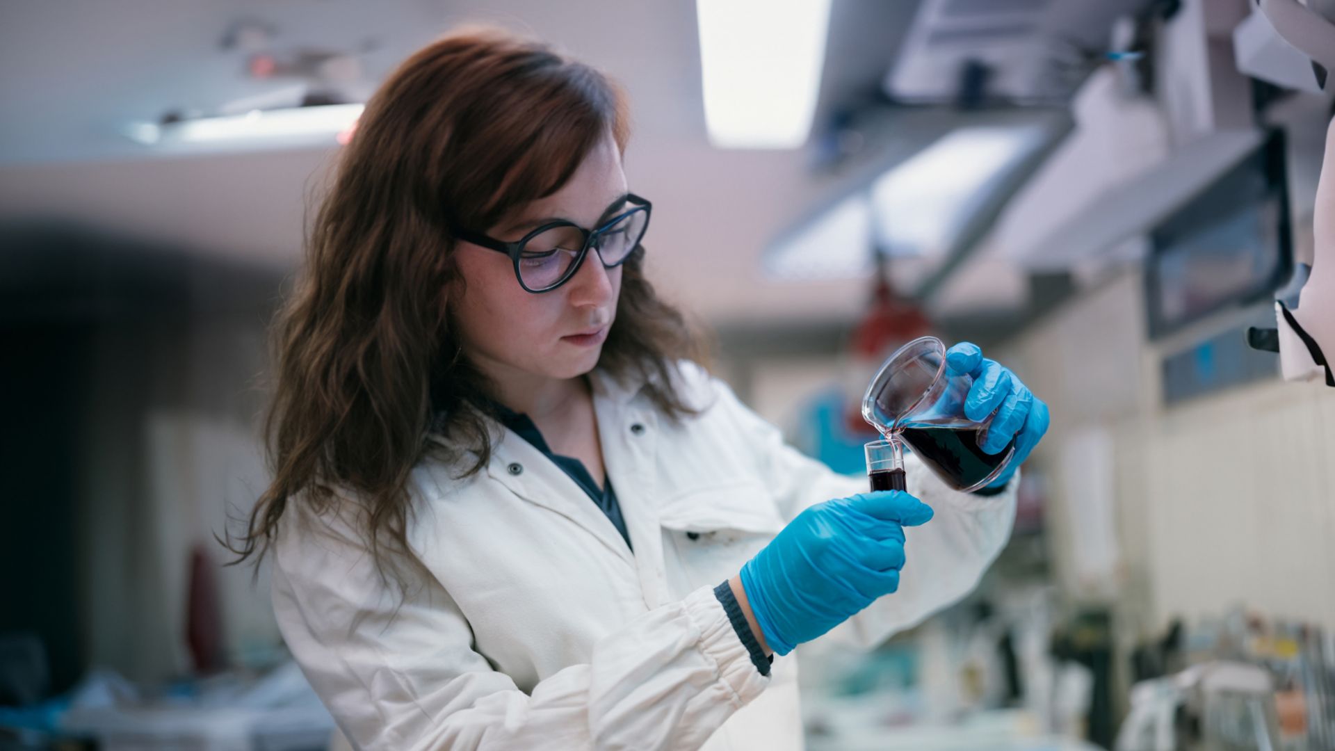 Scienziata in laboratorio mentre utilizza provette per fare test con liquidi neri