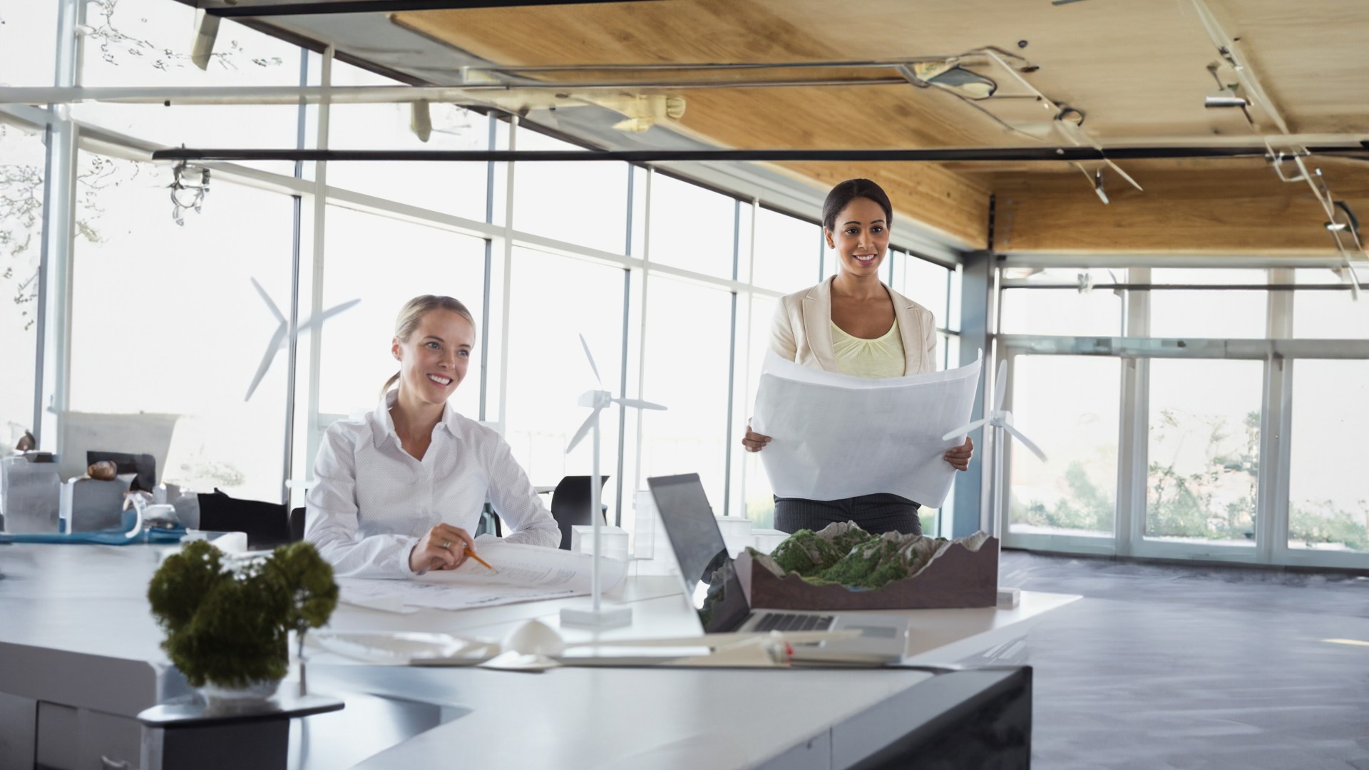 Employees discuss around the table on sustainable projects with model wind turbine blades