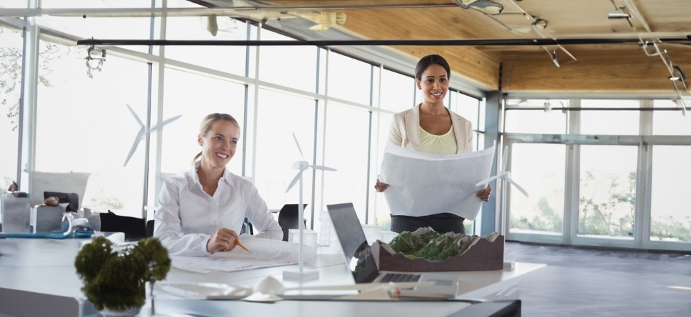 Employees discuss around the table on sustainable projects with model wind turbine blades