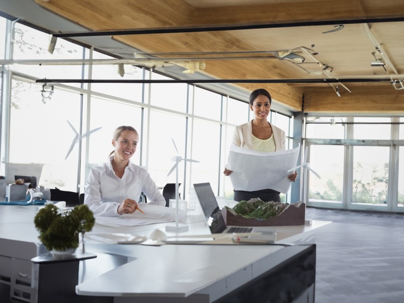 Employees discuss around the table on sustainable projects with model wind turbine blades
