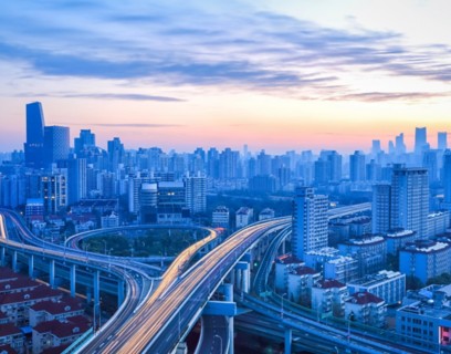 Veduta urbana con autostrade sopraelevate che si intrecciano tra grattacieli moderni, simbolo di mobilità e sviluppo urbano sostenibile.