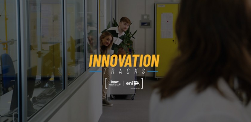 Tre persone sbirciano da un laboratorio mentre una quarta è in primo piano; testo ‘Innovation Tracks’ sovrapposto