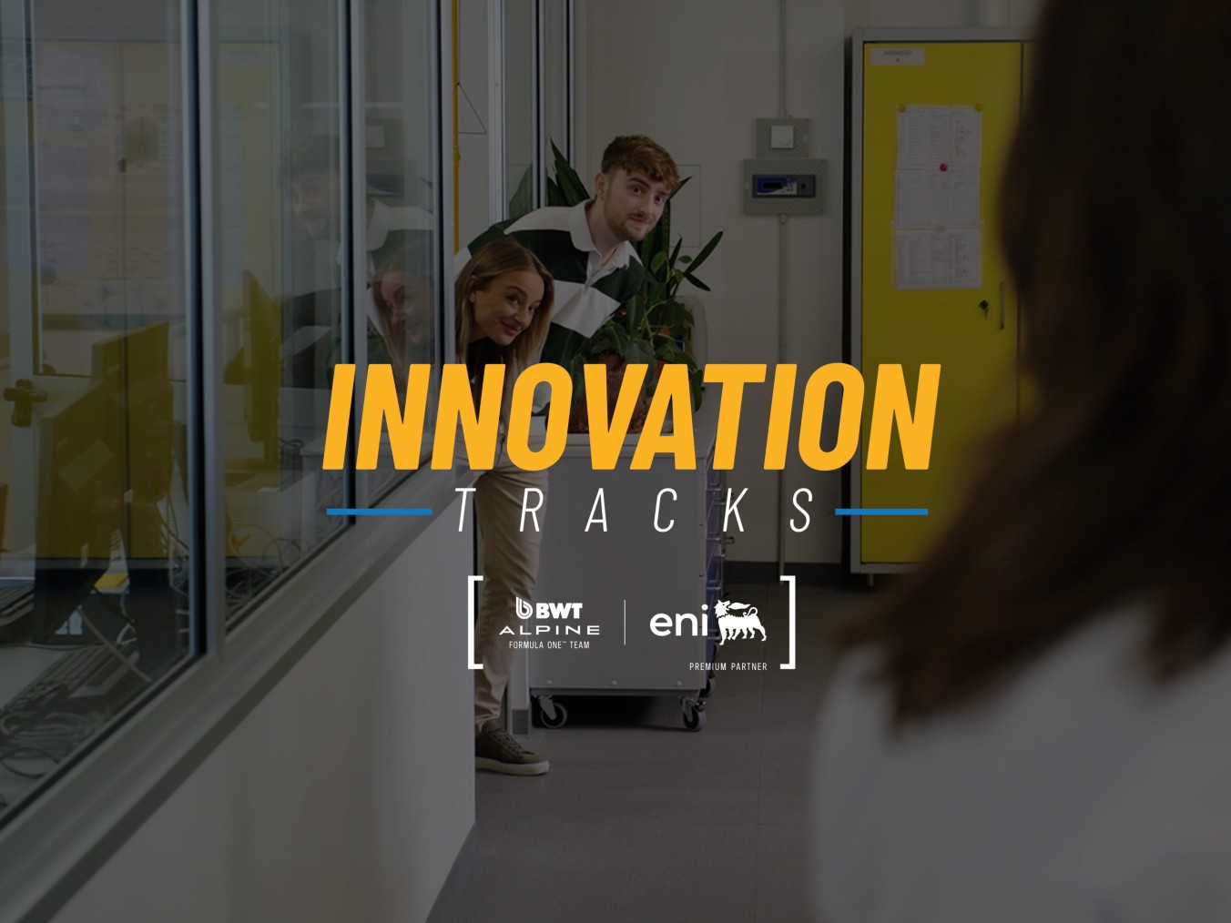 Three people peek out from a lab doorway while another stands in the foreground; overlaid text reads ‘Innovation Tracks.