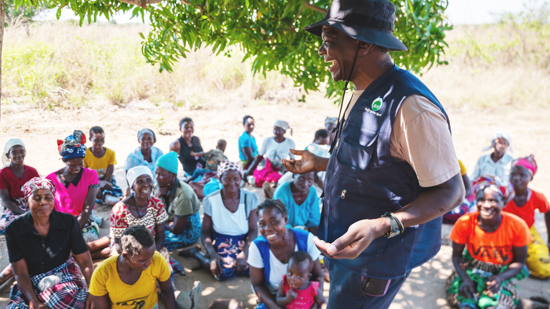 An African man is laughing in front of some women.