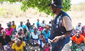 An African man is laughing in front of some women.