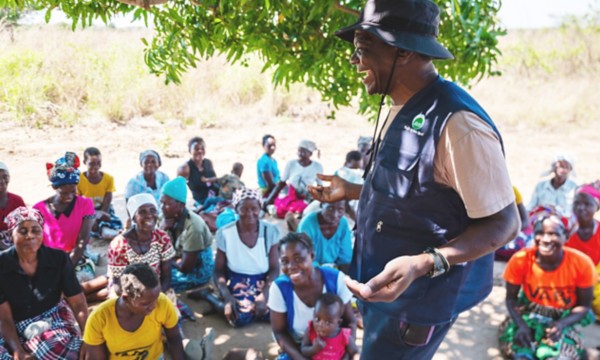 An African man is laughing in front of some women.