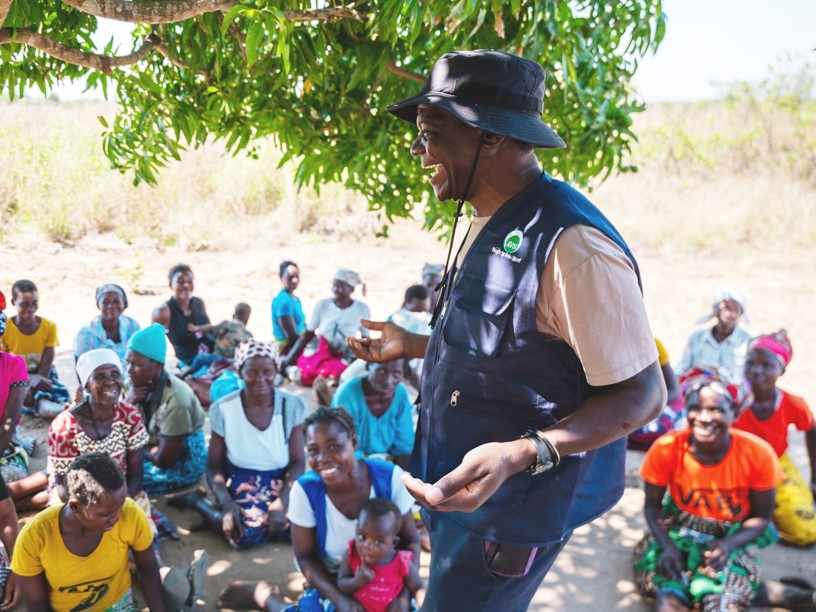An African man is laughing in front of some women.