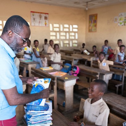 Insegnante africano distribuisce libri in classe agli alunni