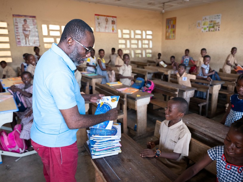 Teacher hands out classroom books to pupils