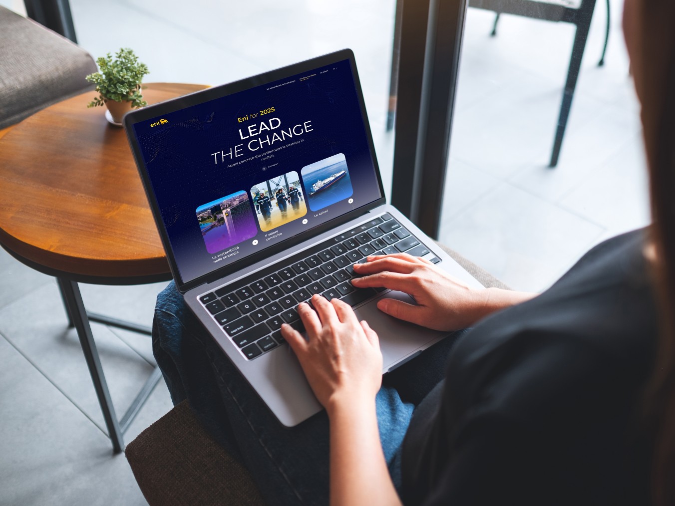 Donna seduta che lavora al computer portatile con il sito ‘Eni for 2025 – Lead the Change’ aperto sullo schermo