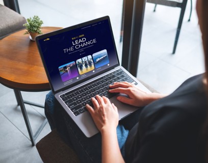Donna seduta che lavora al computer portatile con il sito ‘Eni for 2025 – Lead the Change’ aperto sullo schermo