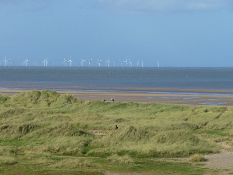 Foto panoramica raffigurante una spiaggia inglese con pale eoliche offshore all'orizzonte
