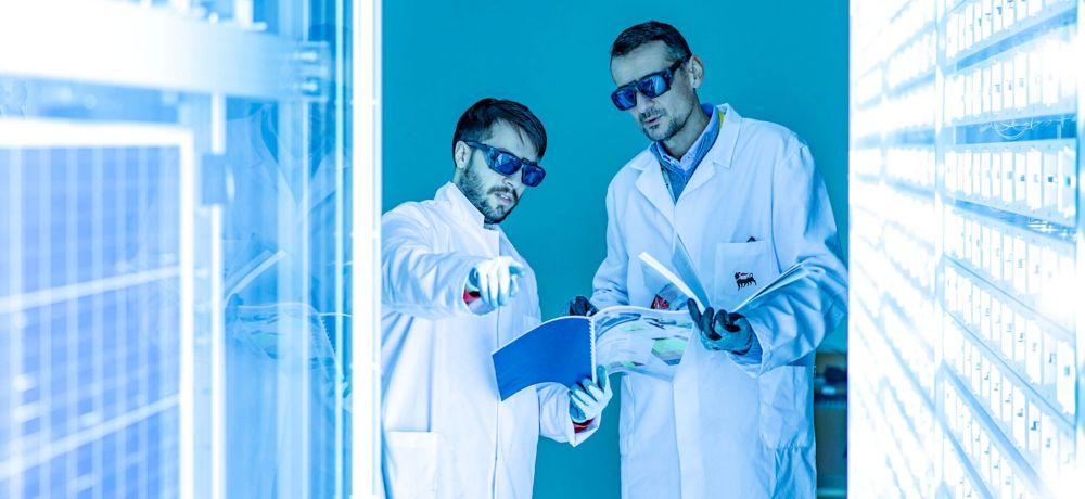 Due scienziati all'interno del laboratorio mentre analizzano i pannelli intorno a loro