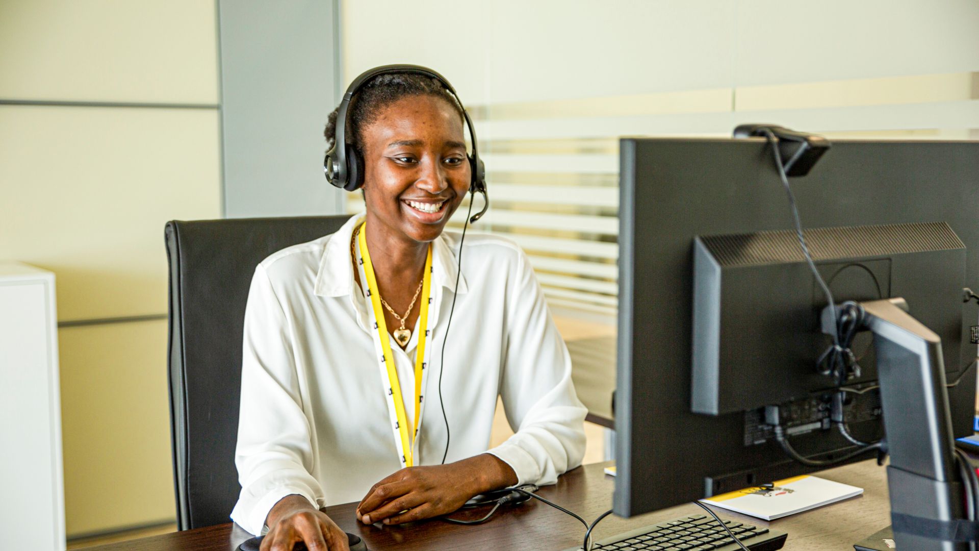 African Eni employee smiles in front of computer