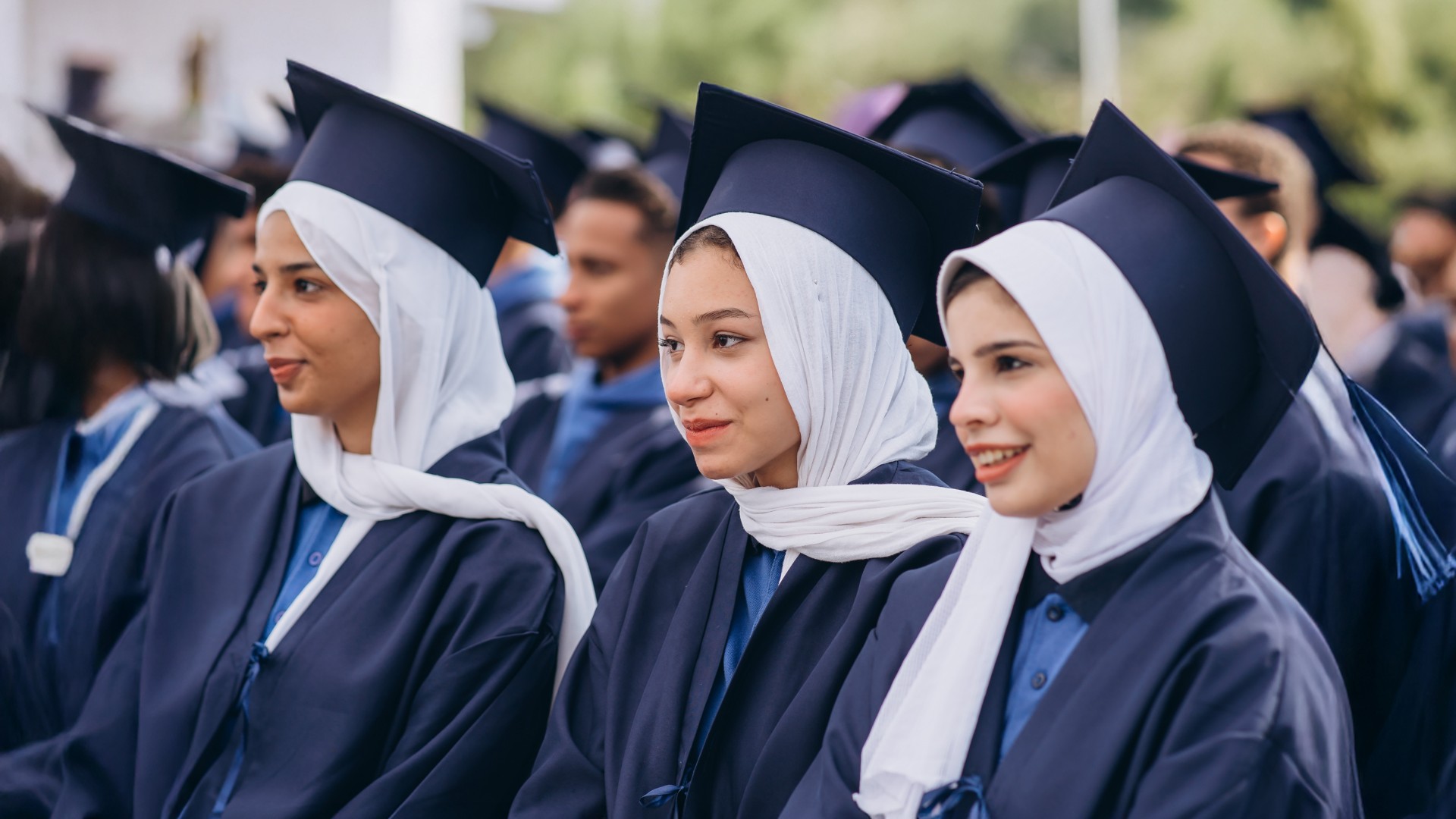Three female students sitting together during the graduation ceremony