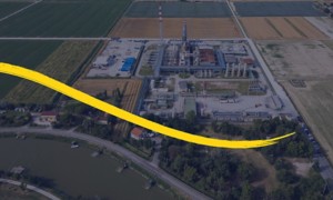 Veduta aerea di impianto industriale con pennellata gialla curva in basso.