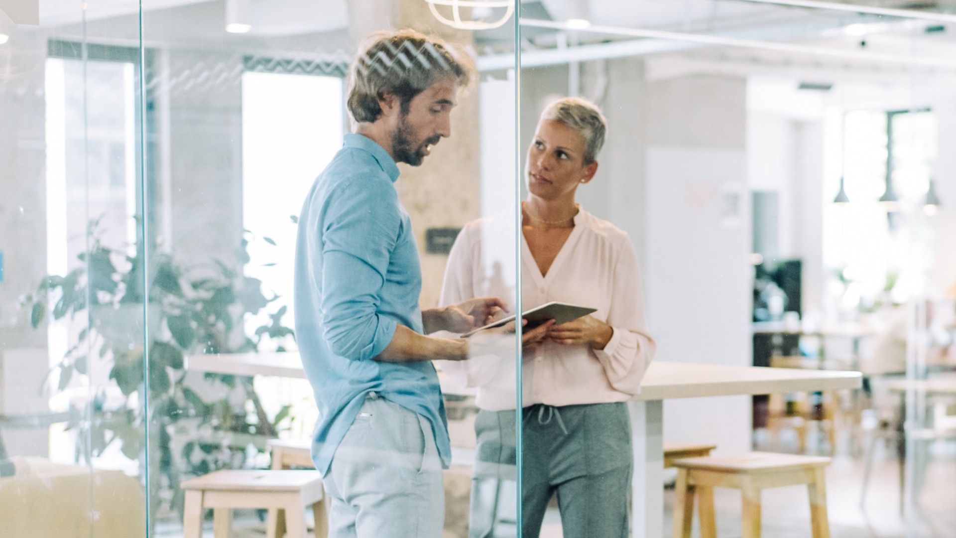 Man and woman in office discussing with ipad in hand