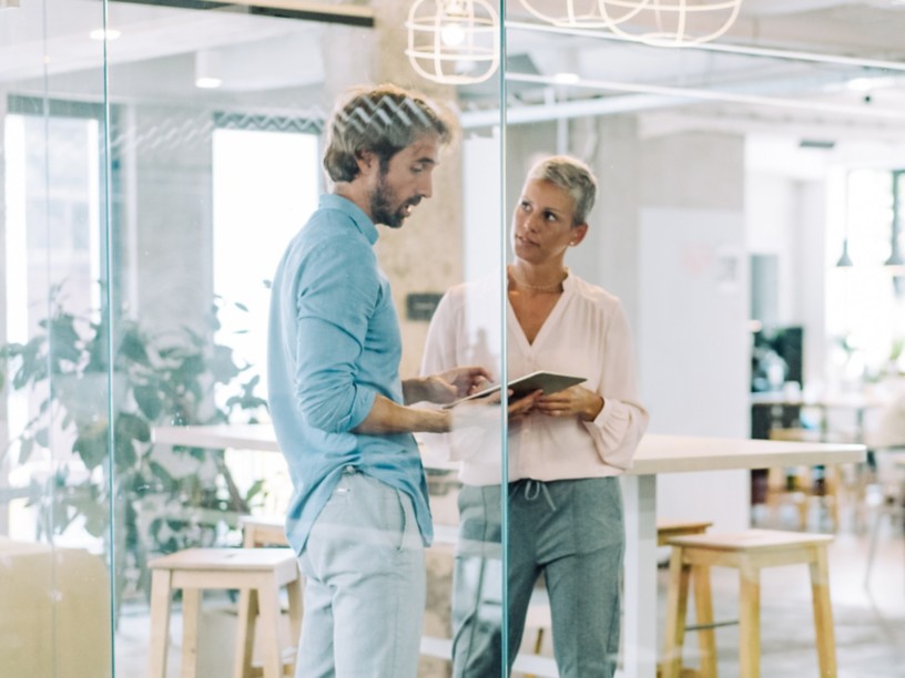 Man and woman in office discussing with ipad in hand