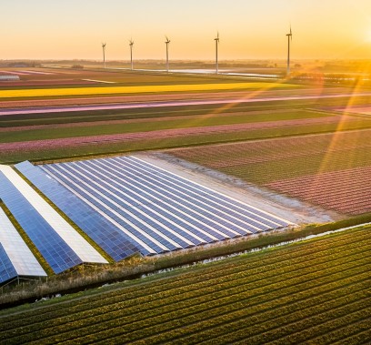 Vista di pannelli solari e pale eoliche in campo con tramonto