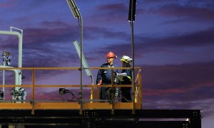due operai sul ponteggio di un cantiere illuminato al tramonto