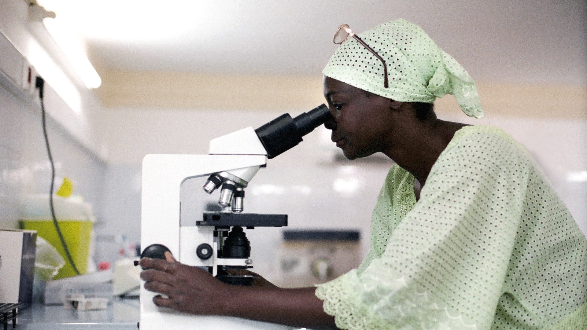 African doctor looks through microscope