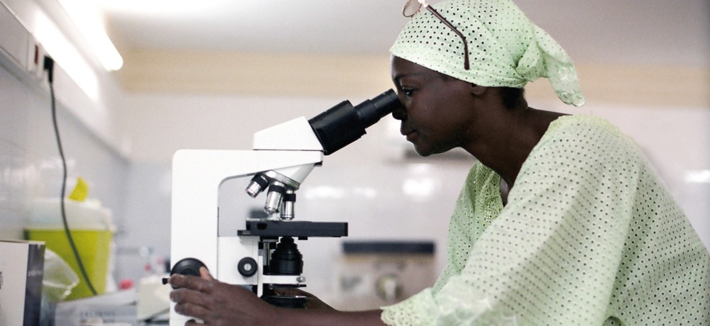 African doctor looks through microscope