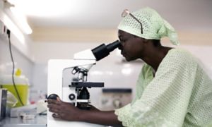 African doctor looks through microscope