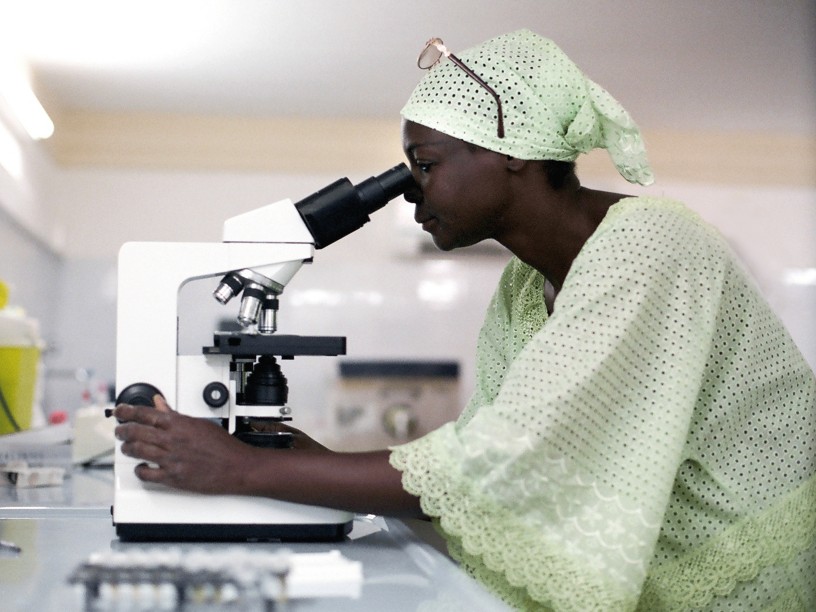 Woman looks through a microscope inside a laboratory