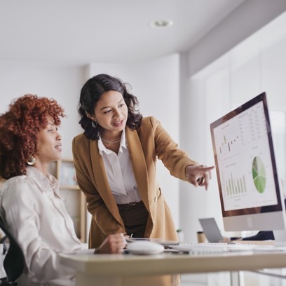 Two female colleagues in the office look at monitor data