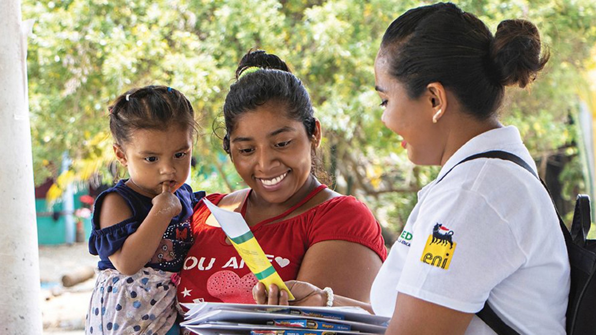 Mexican woman hands out information leaflet to Mexican woman with child