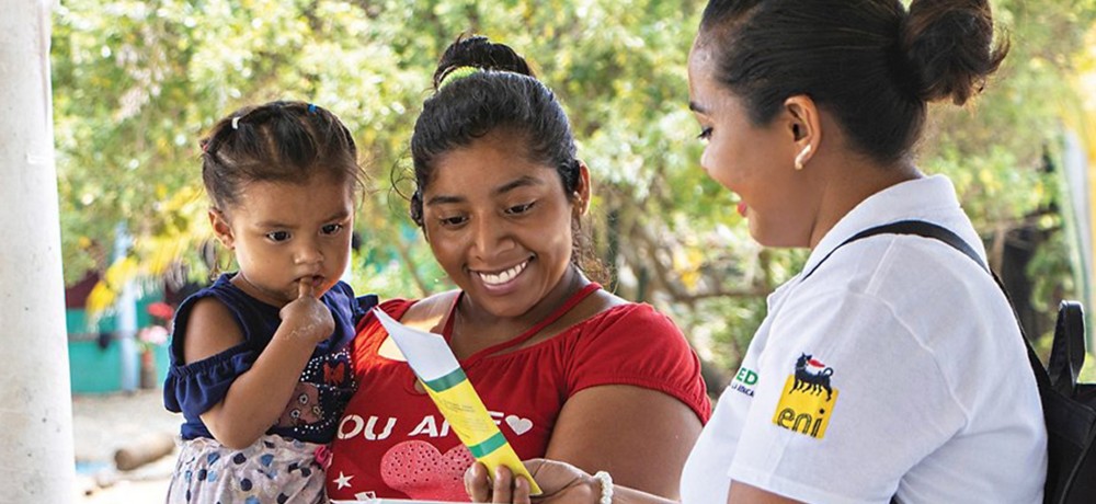 Mexican woman hands out information leaflet to Mexican woman with child