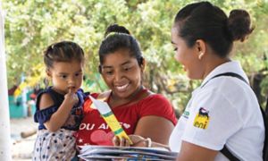 Mexican woman hands out information leaflet to Mexican woman with child