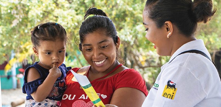 Mexican woman hands out information leaflet to Mexican woman with child